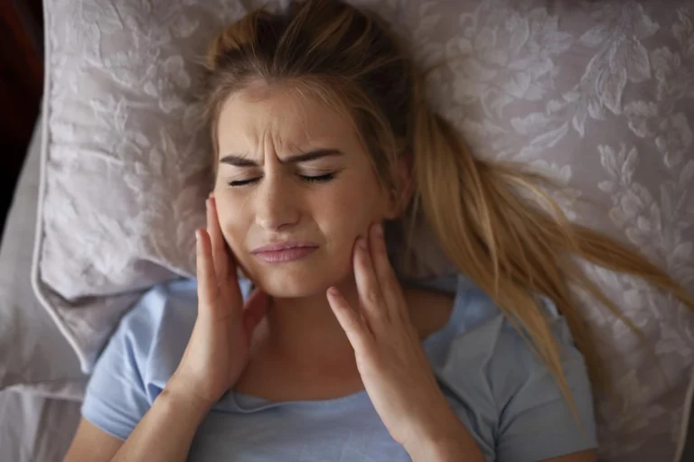 a woman lying iin bde suffering from TMJ disorder